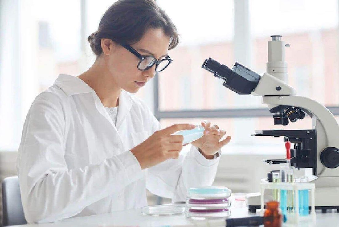 A researcher in a laboratory examining a sample under a microscope